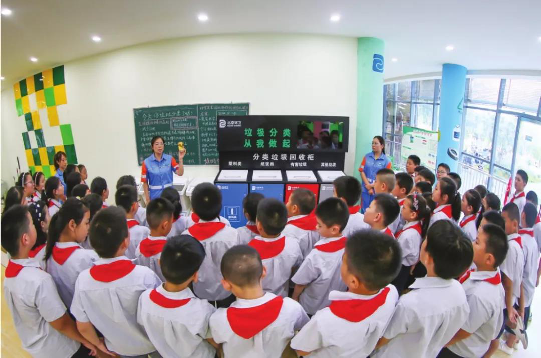 小学生认真聆听环卫工人讲解垃圾分类的重要意义